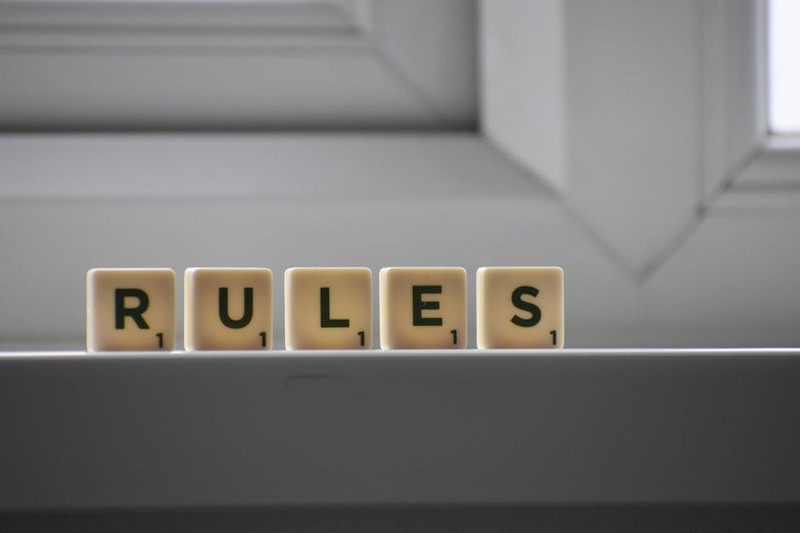 Identical small square shaped cubes with RULES title and numbers on white windowsill near window in 