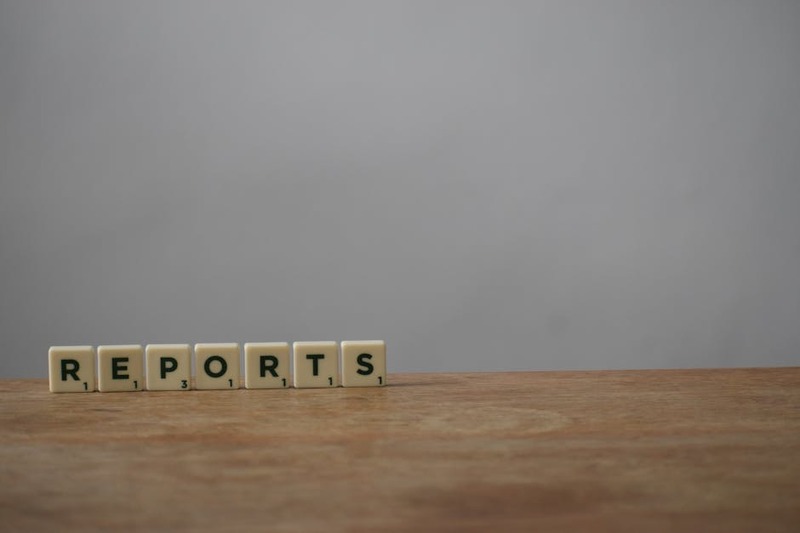 Scrabble tiles spelling 'reports' on a wooden desk, ideal for office or business themes.