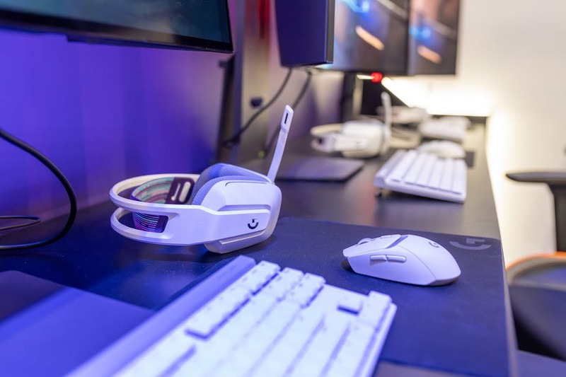 A clean desk setup with a high-end wireless gaming headset, keyboard, and monitor